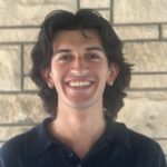 Tobias standing next to a brick wall.