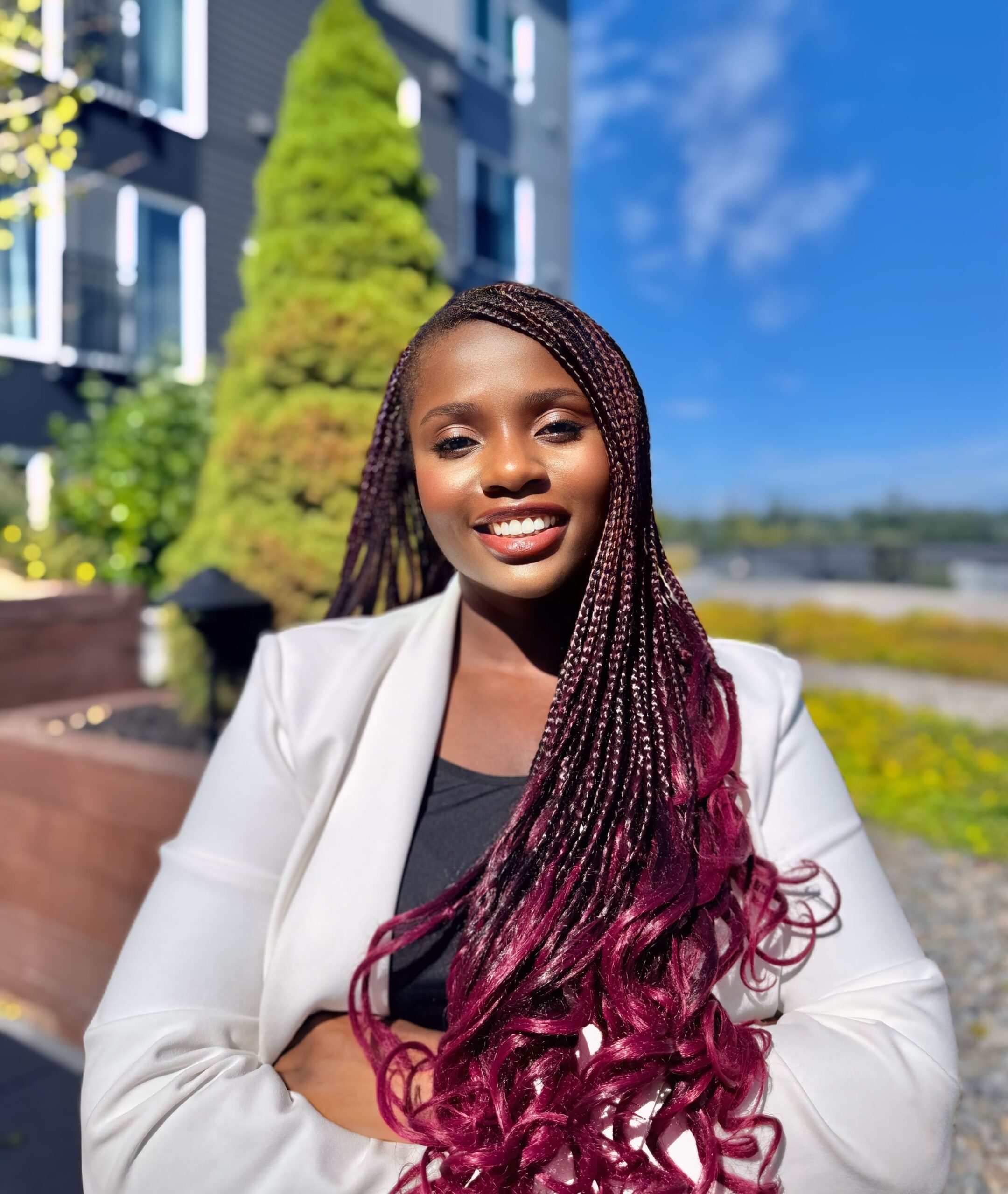Anna is outside in front of a building on a sunny day.