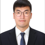 Juyoung in front of a white wall, wearing a suit.