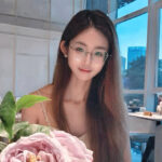 Tingli Qian is sitting in front of some flowers.