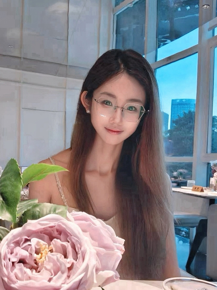 Tingli Qian is sitting in front of some flowers.