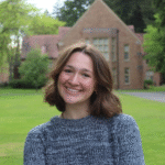 Jordan standing outside in front of a building, wearing a blue sweater.