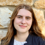 Madelyn standing outside in front of a brick wall,