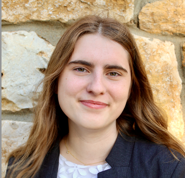 Madelyn standing outside in front of a brick wall,